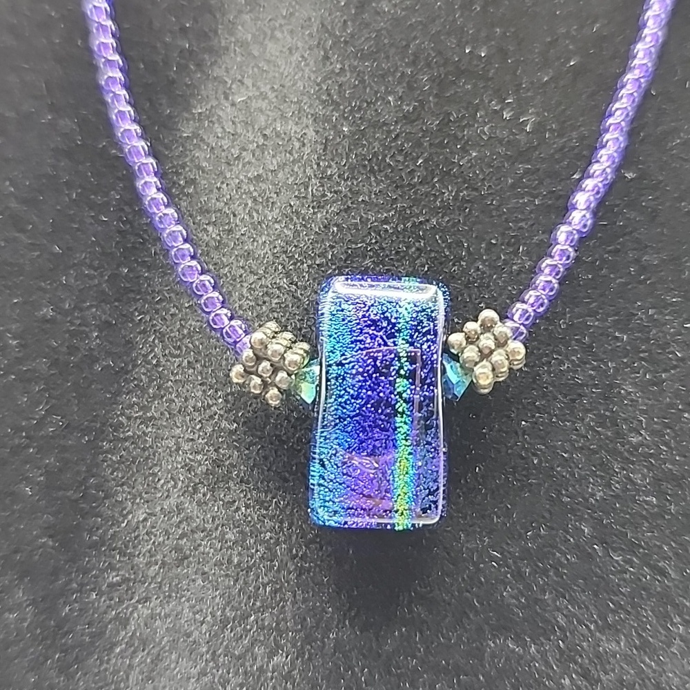 Handmade‎ dichroic fused glass pendant necklace on a purple beaded chain.